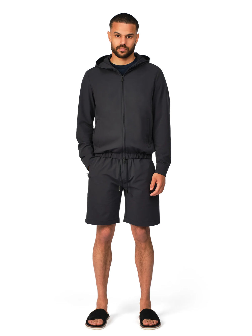 Man wearing a black hoodie and shorts set on a white background