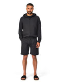 Man wearing a black hoodie and shorts set on a white background