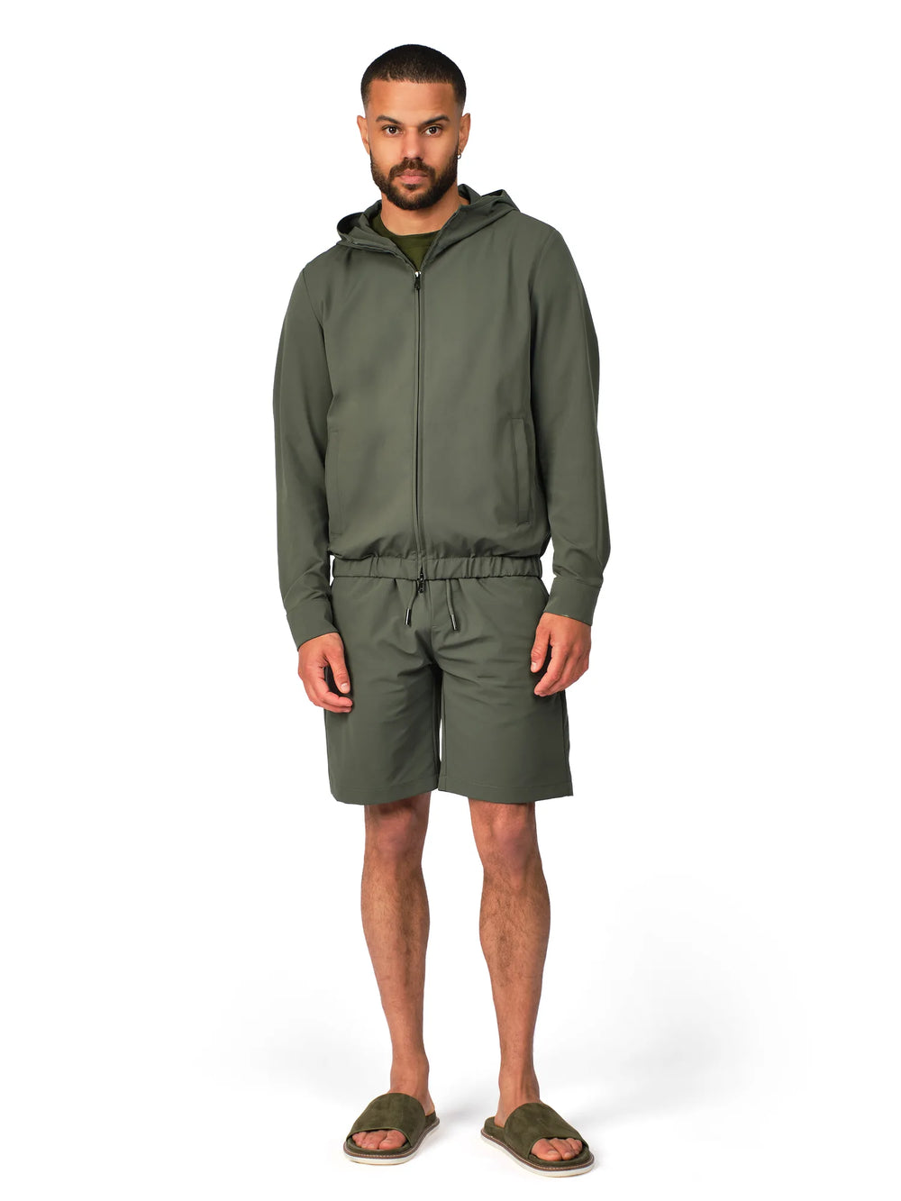 Man wearing a green hoodie and shorts set on a white background