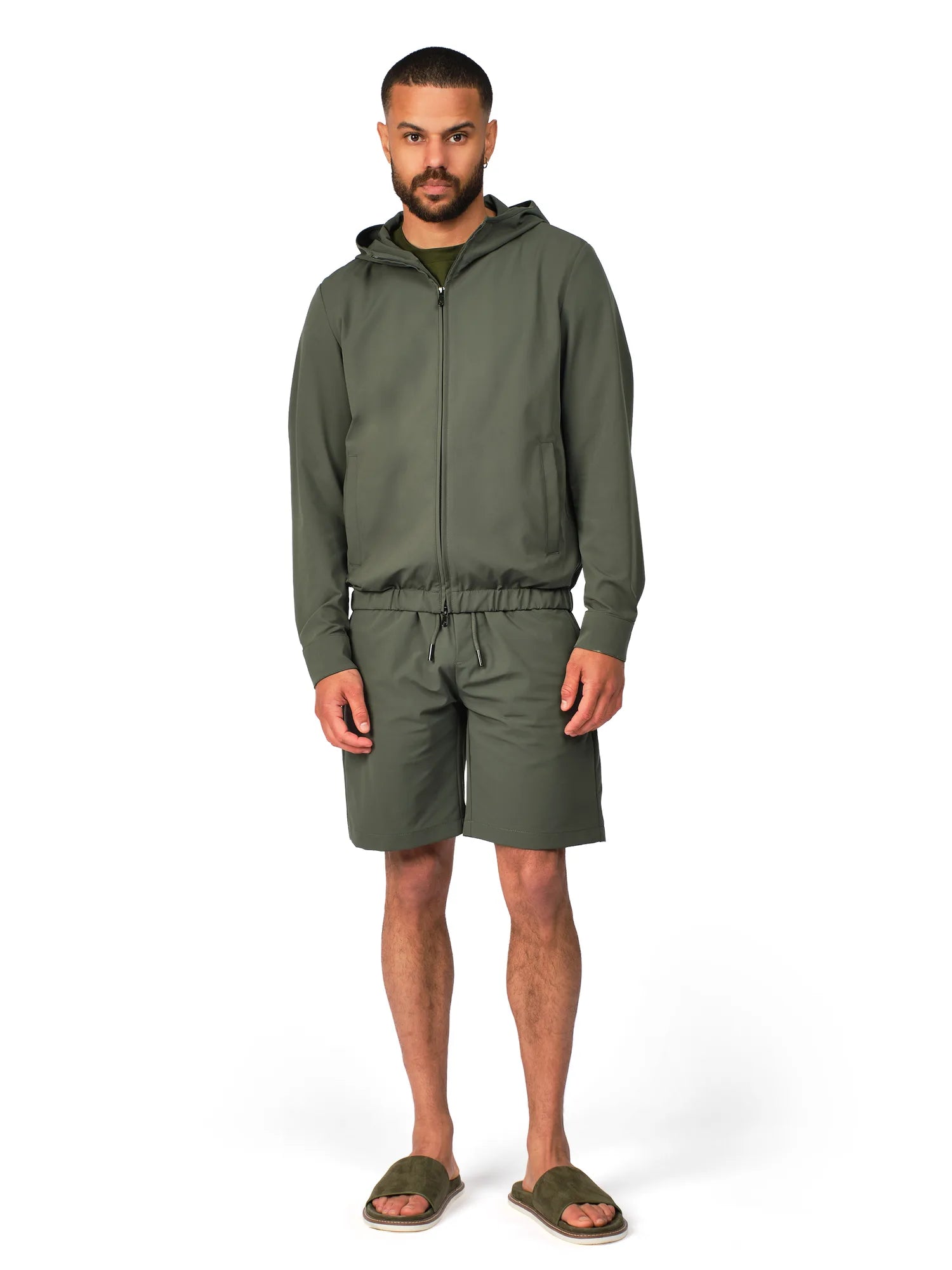Man wearing a green hoodie and shorts set on a white background
