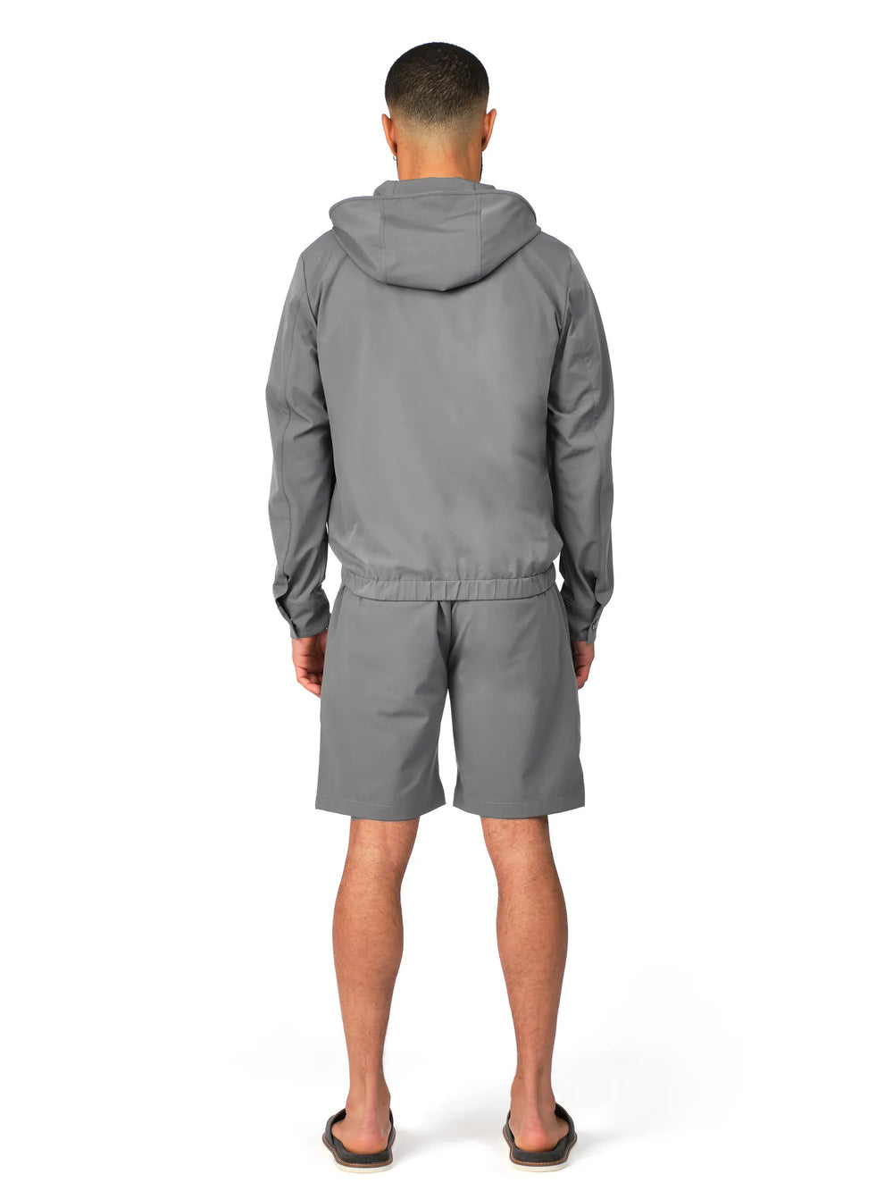 Person wearing a gray tracksuit on a white background