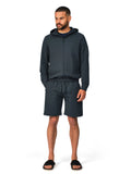 Man wearing a dark gray hoodie and shorts set on a white background