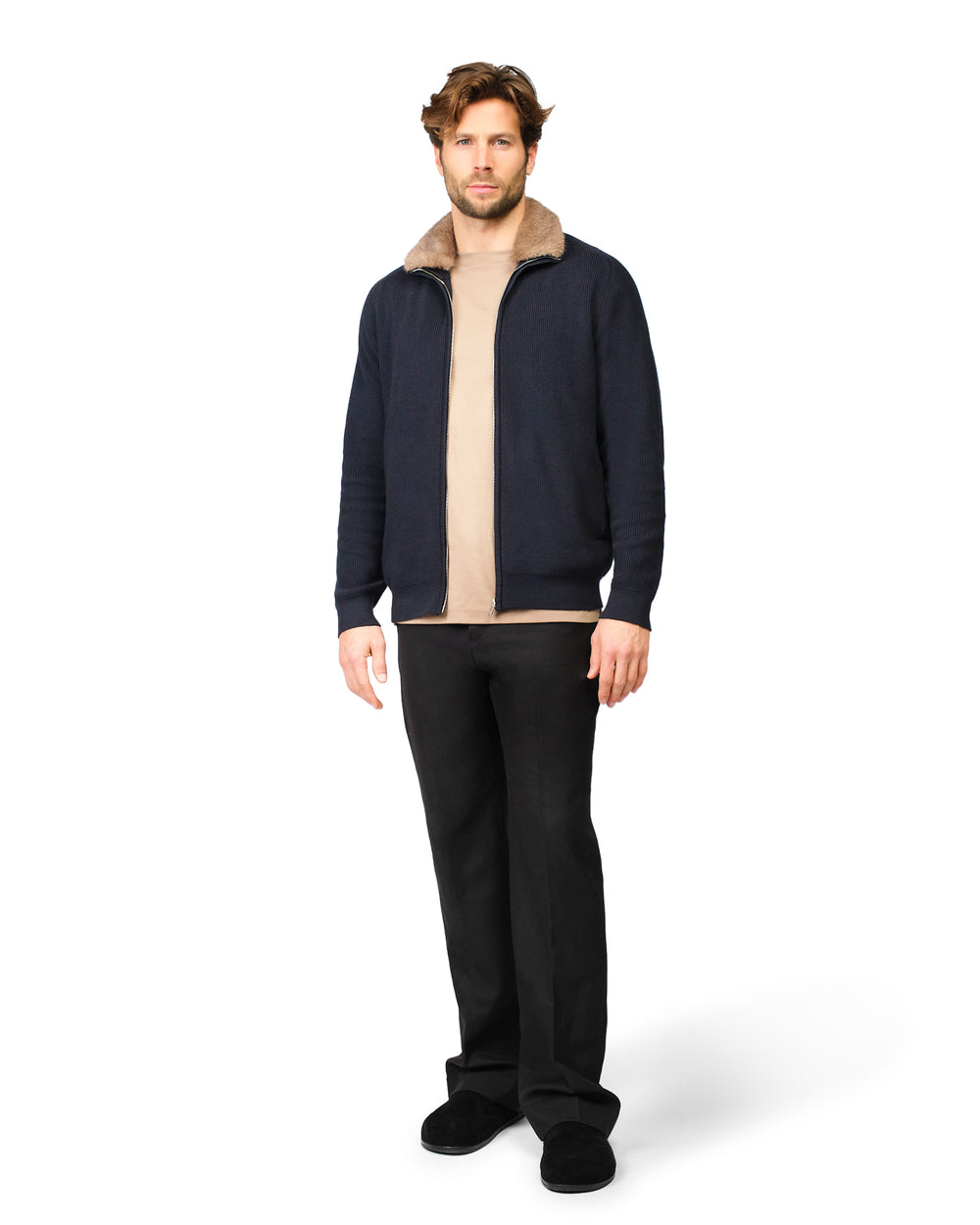 Man wearing a navy jacket with a beige collar and black pants on a white background