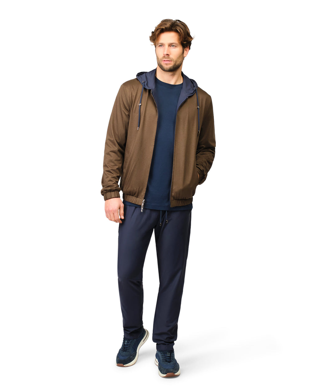 Man wearing a brown jacket and navy pants on a white background