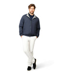 Man wearing a navy jacket and white pants on a white background