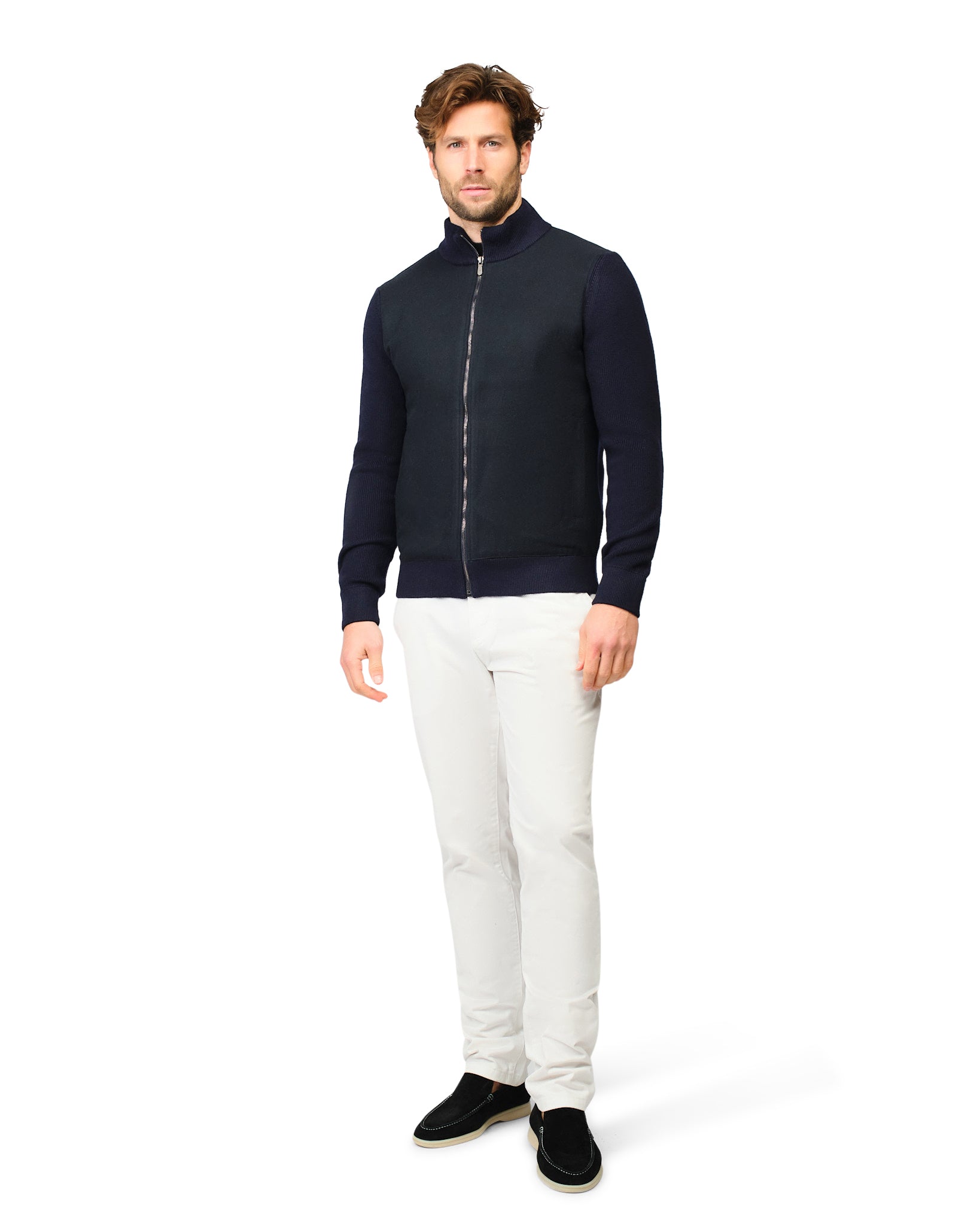 Man wearing a navy blue jacket and white pants on a white background
