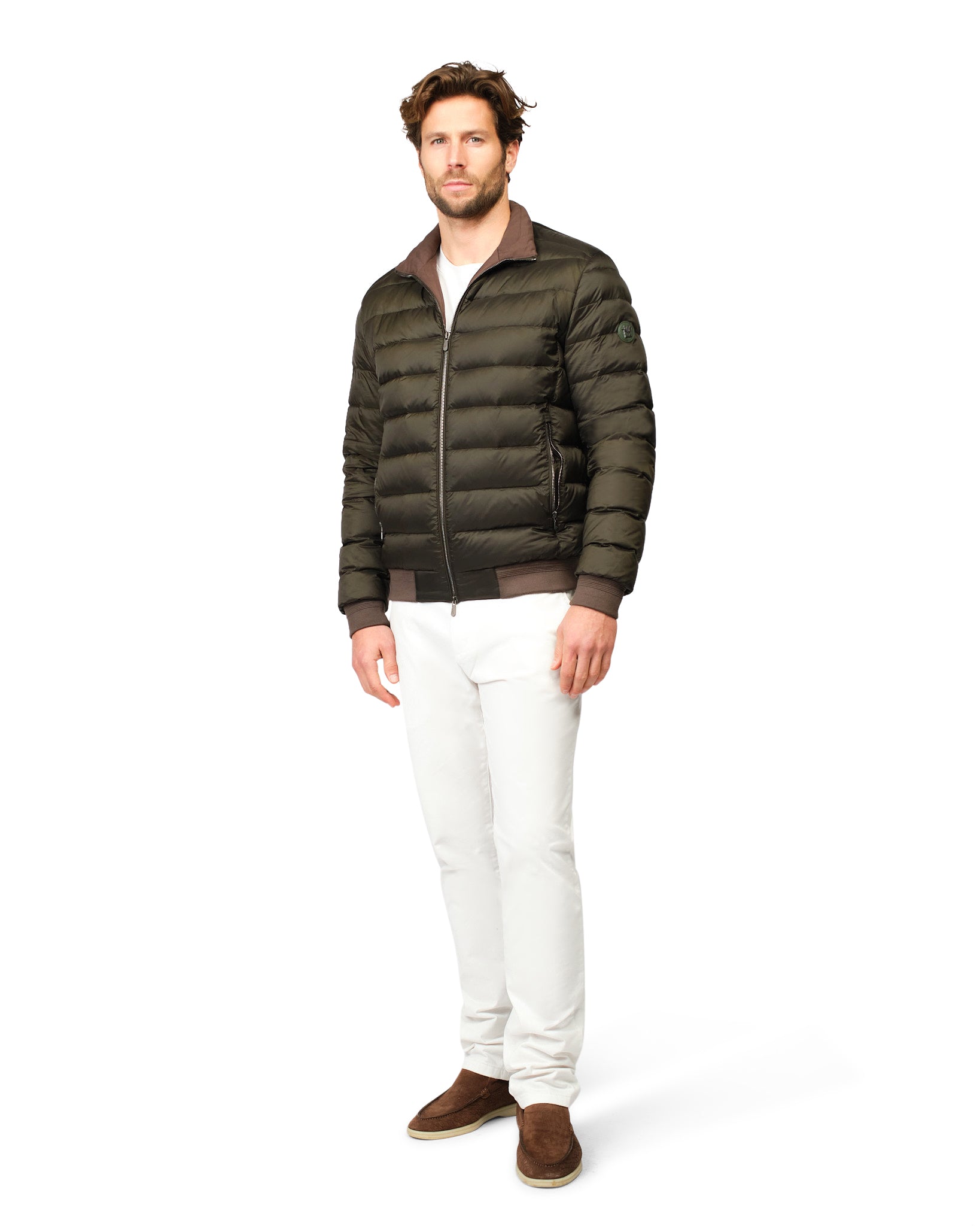 Man wearing a green puffer jacket and white pants on a white background