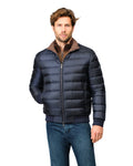 Man wearing a navy blue puffer jacket with a brown collar on a white background