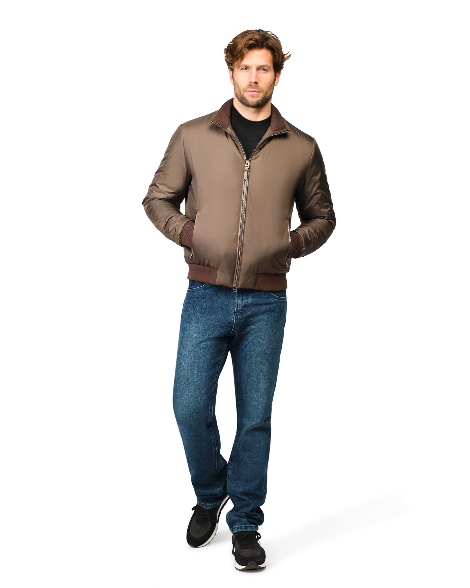 Man wearing a brown bomber jacket and blue jeans on a white background