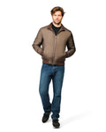 Man wearing a brown bomber jacket and blue jeans on a white background