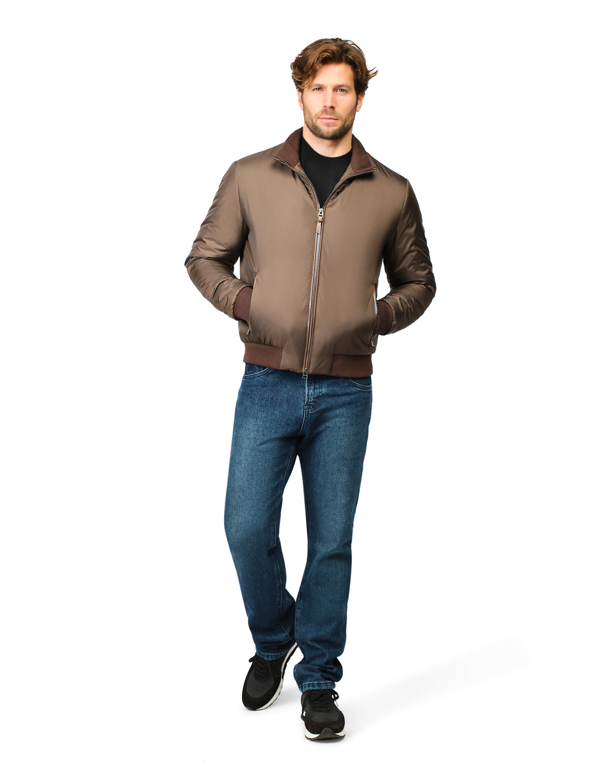 Man wearing a brown bomber jacket and blue jeans on a white background