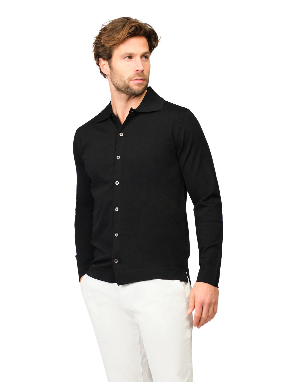 Man wearing a black button-up shirt and white pants on a white background