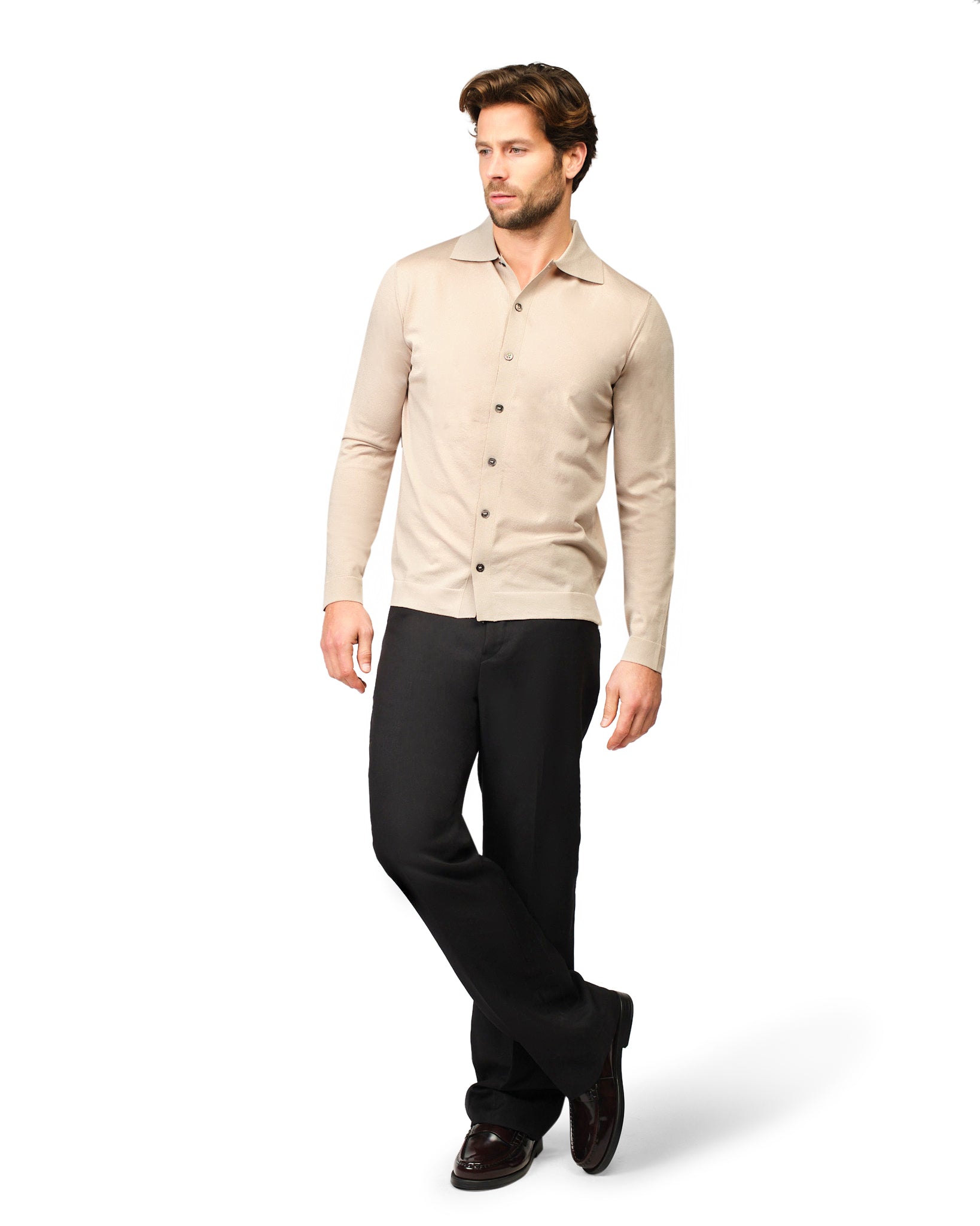 Man wearing a beige shirt and black pants on a white background