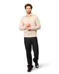 Man wearing a beige sweater and black pants on a white background
