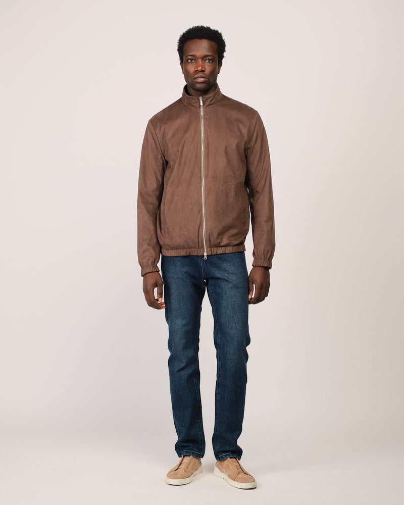 Man wearing a brown jacket and blue jeans on a white background