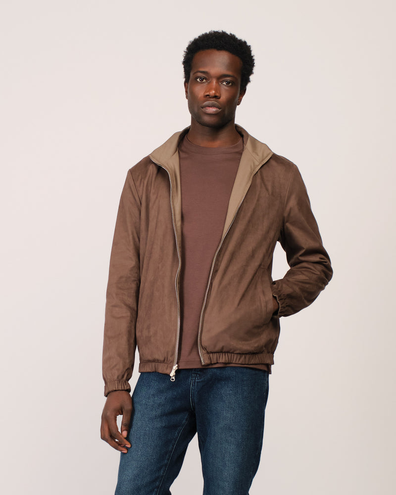 Man wearing a brown jacket over a brown shirt on a plain background