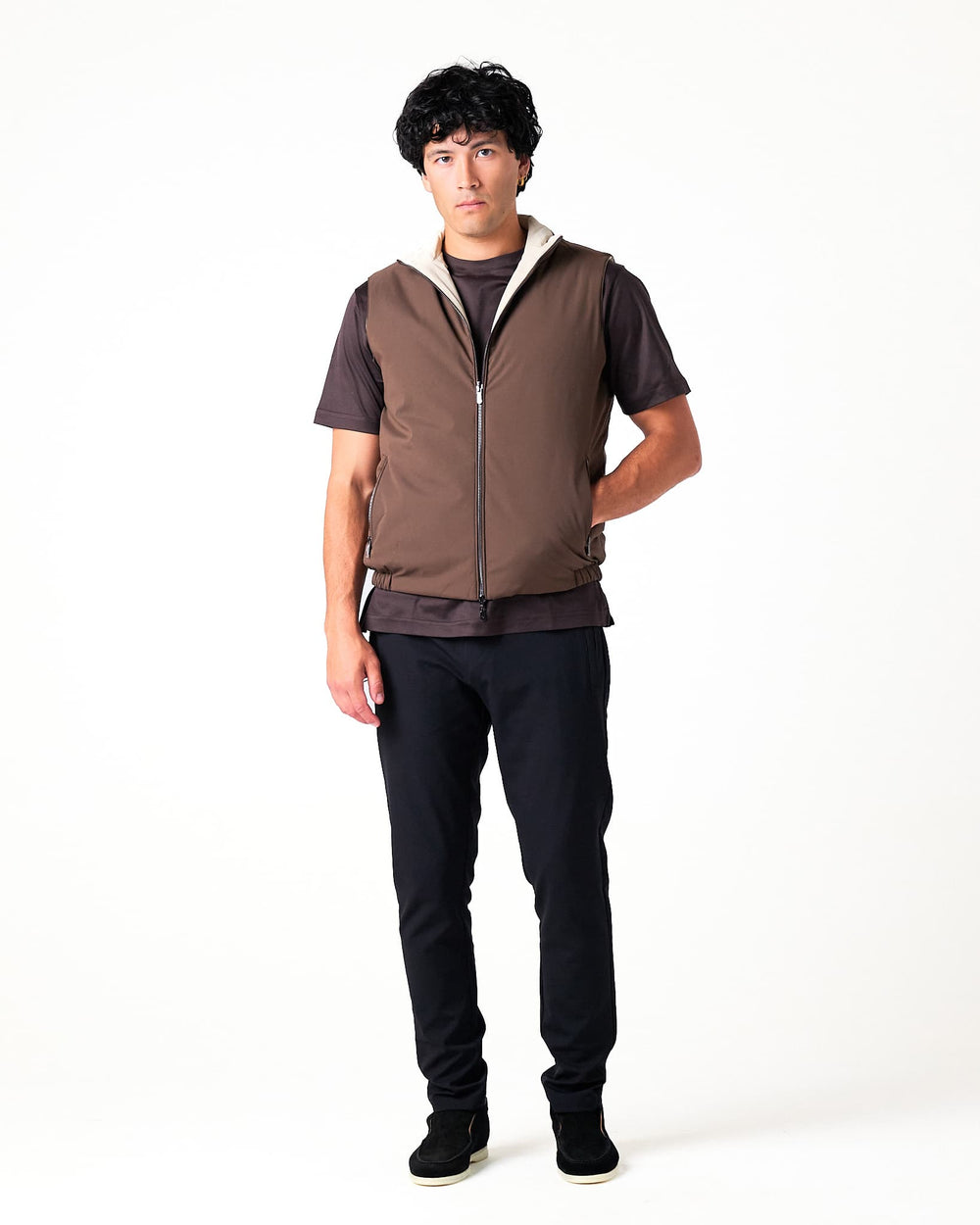 Man wearing a brown vest over a dark shirt on a white background
