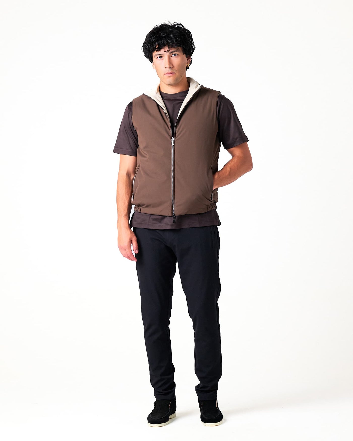 Man wearing a brown vest over a dark shirt on a white background