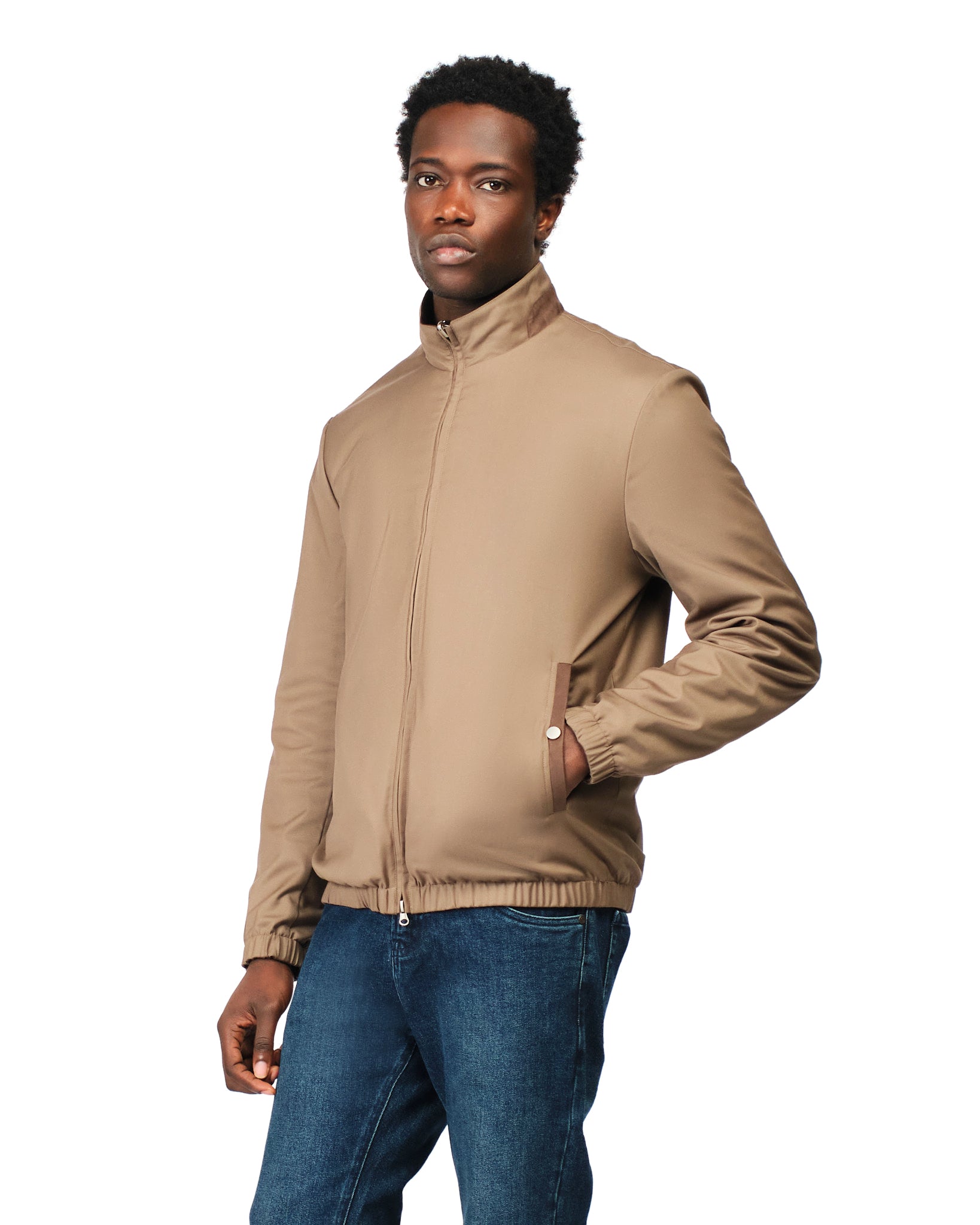 Man wearing a beige jacket and blue jeans on a white background