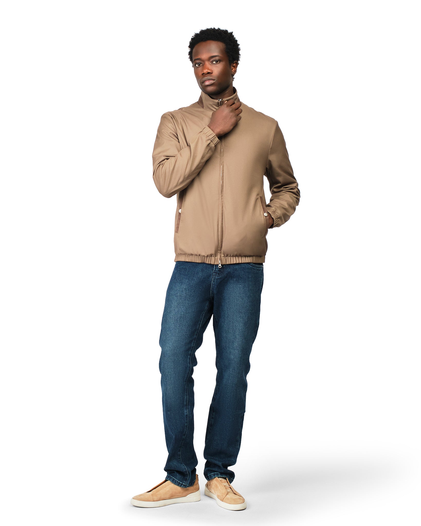 Man wearing a beige jacket and blue jeans on a white background