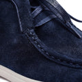 Close-up of a navy blue suede shoe with white sole on a white background