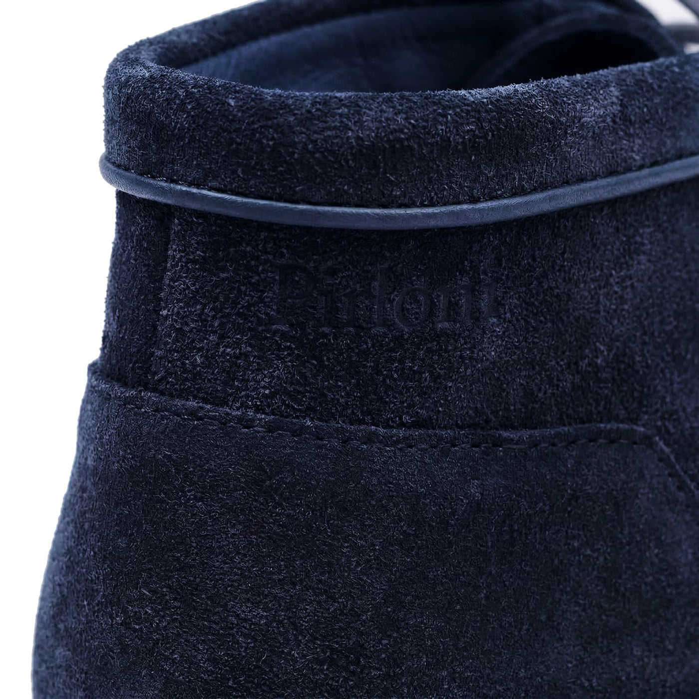 Close-up of a navy blue suede shoe with brand name on a white background