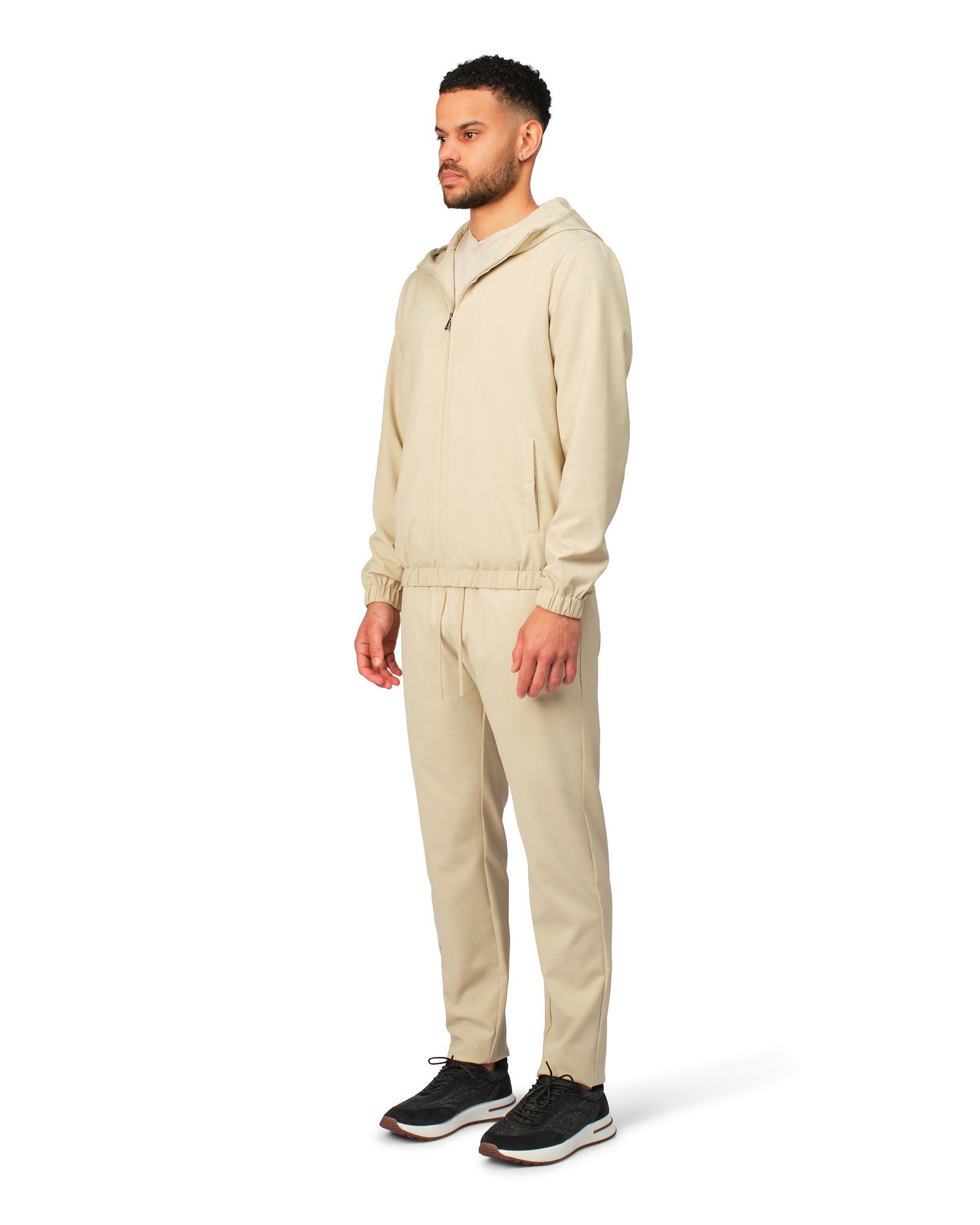 Man wearing a beige tracksuit on a white background