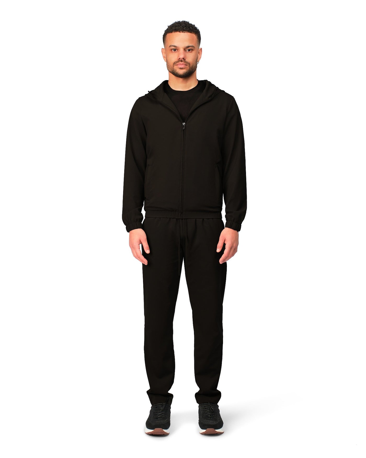 Man wearing a black hoodie and pants on a white background