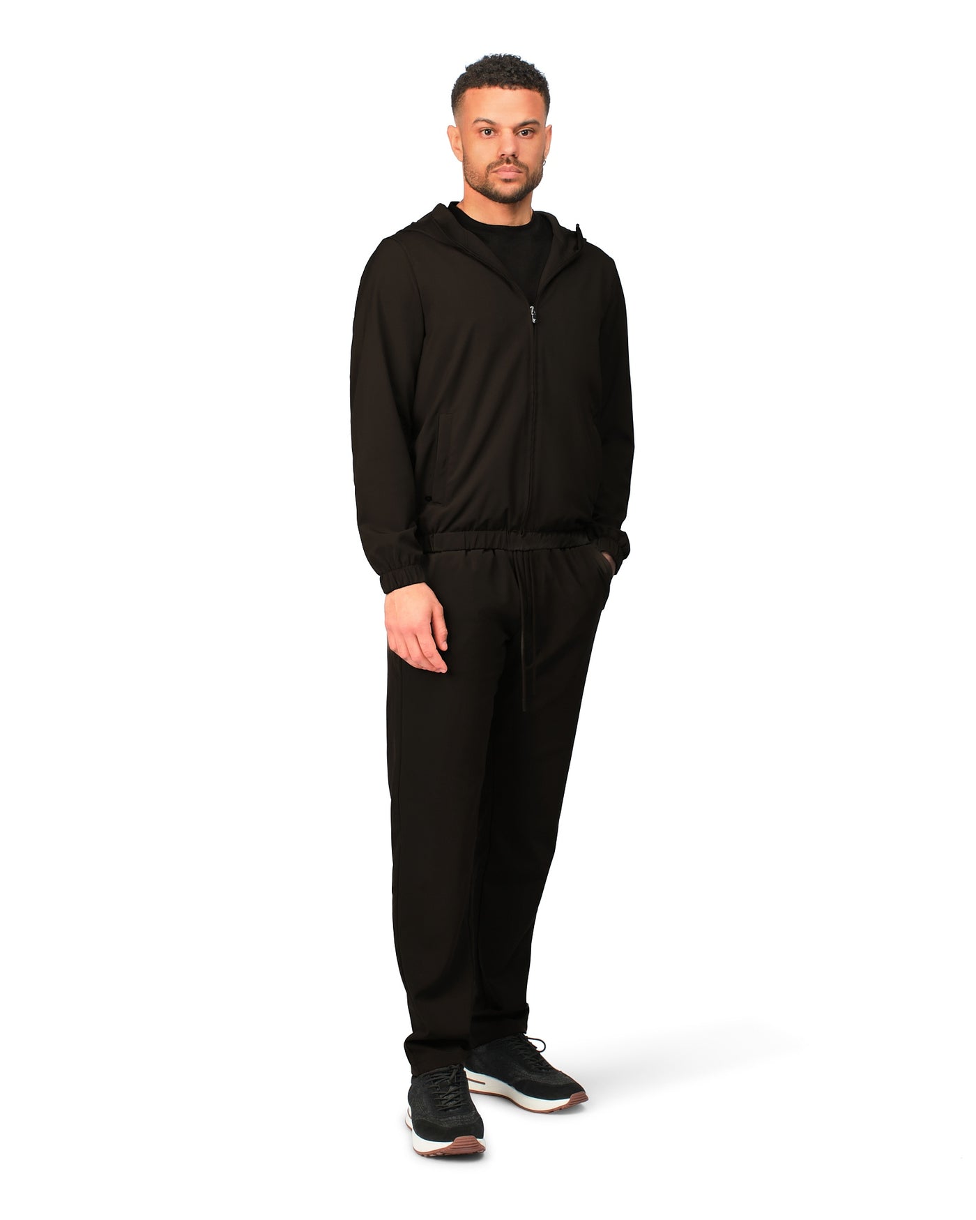 Man wearing a black hoodie and pants on a white background