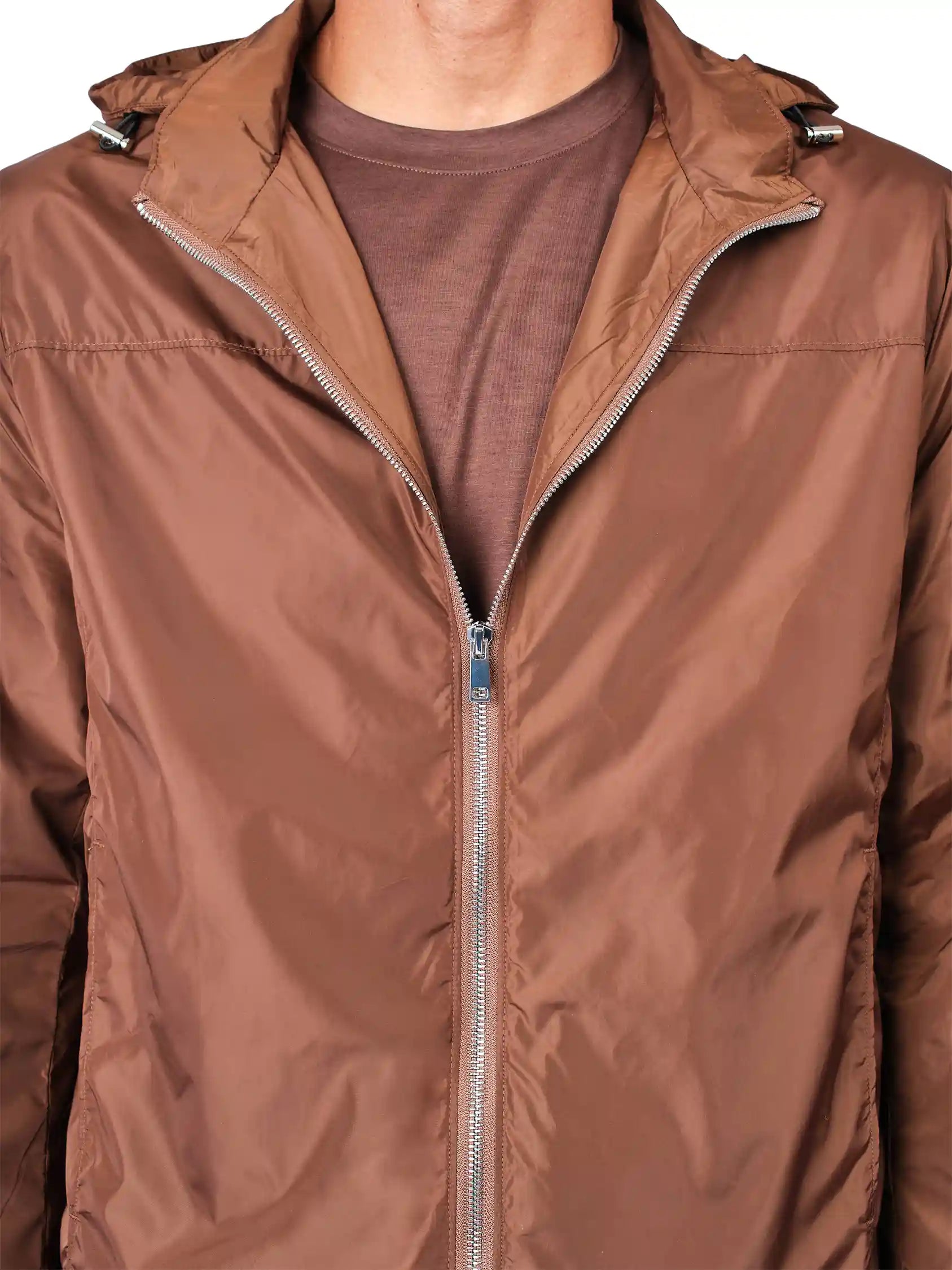 A close-up of a person wearing a brown hooded jacket over a brown t-shirt, showing the front zipper and hood details.