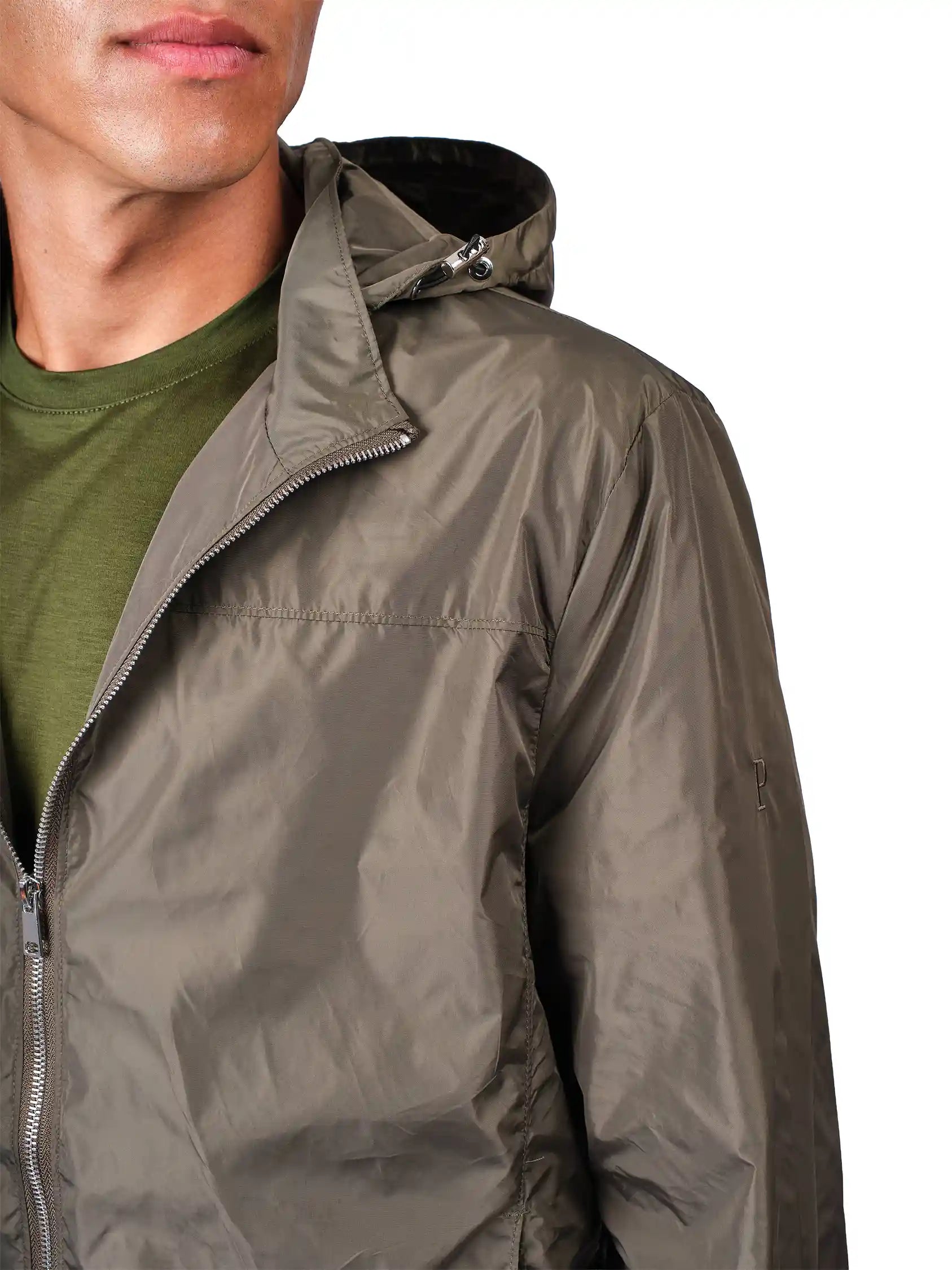 Close-up of a person wearing a hooded zip-front jacket in a muted olive-gray color over an olive green shirt, against a plain white background.