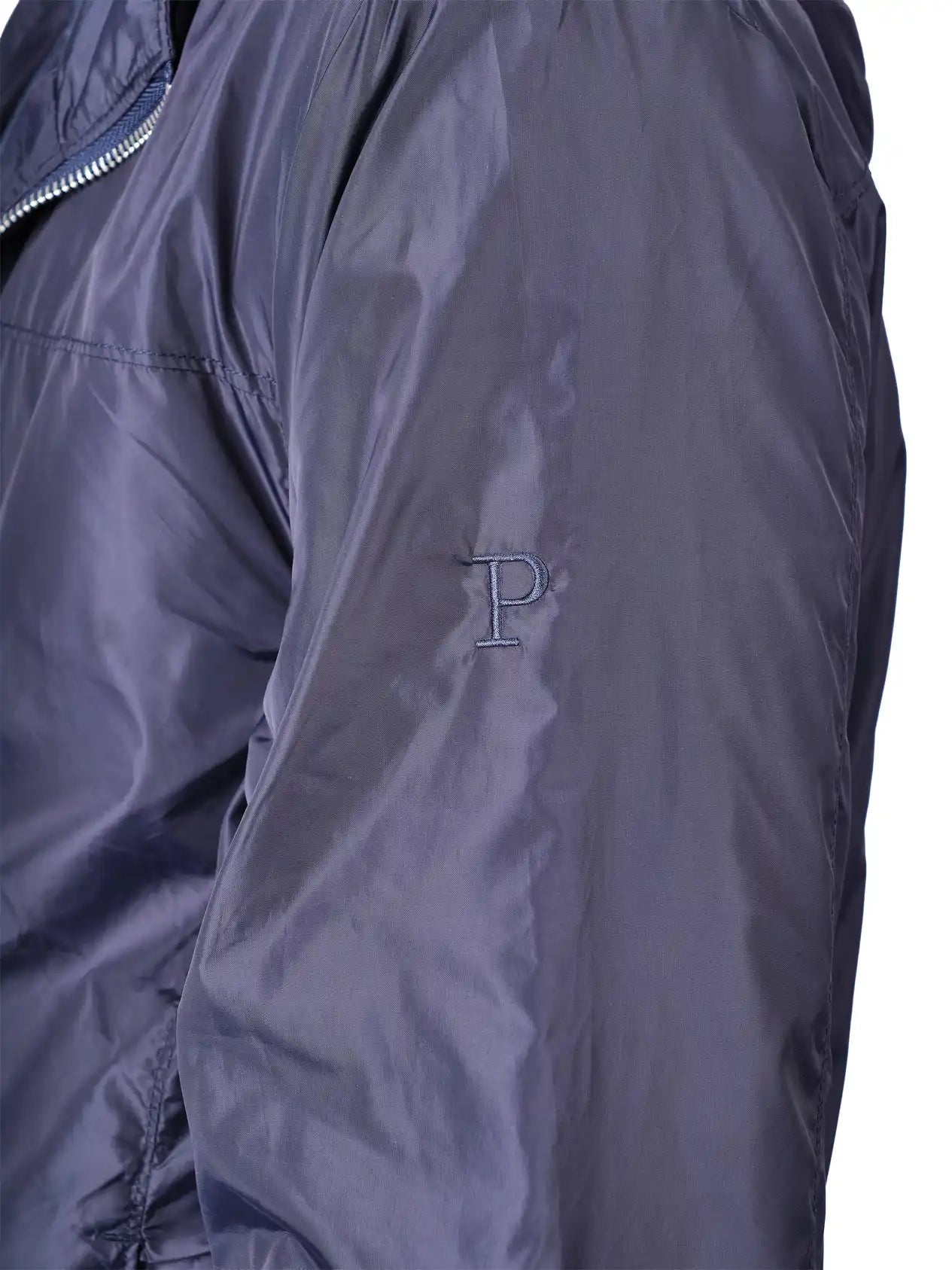 Close-up of a dark slate blue or navy jacket sleeve featuring an embroidered letter 'P' logo on the upper arm.