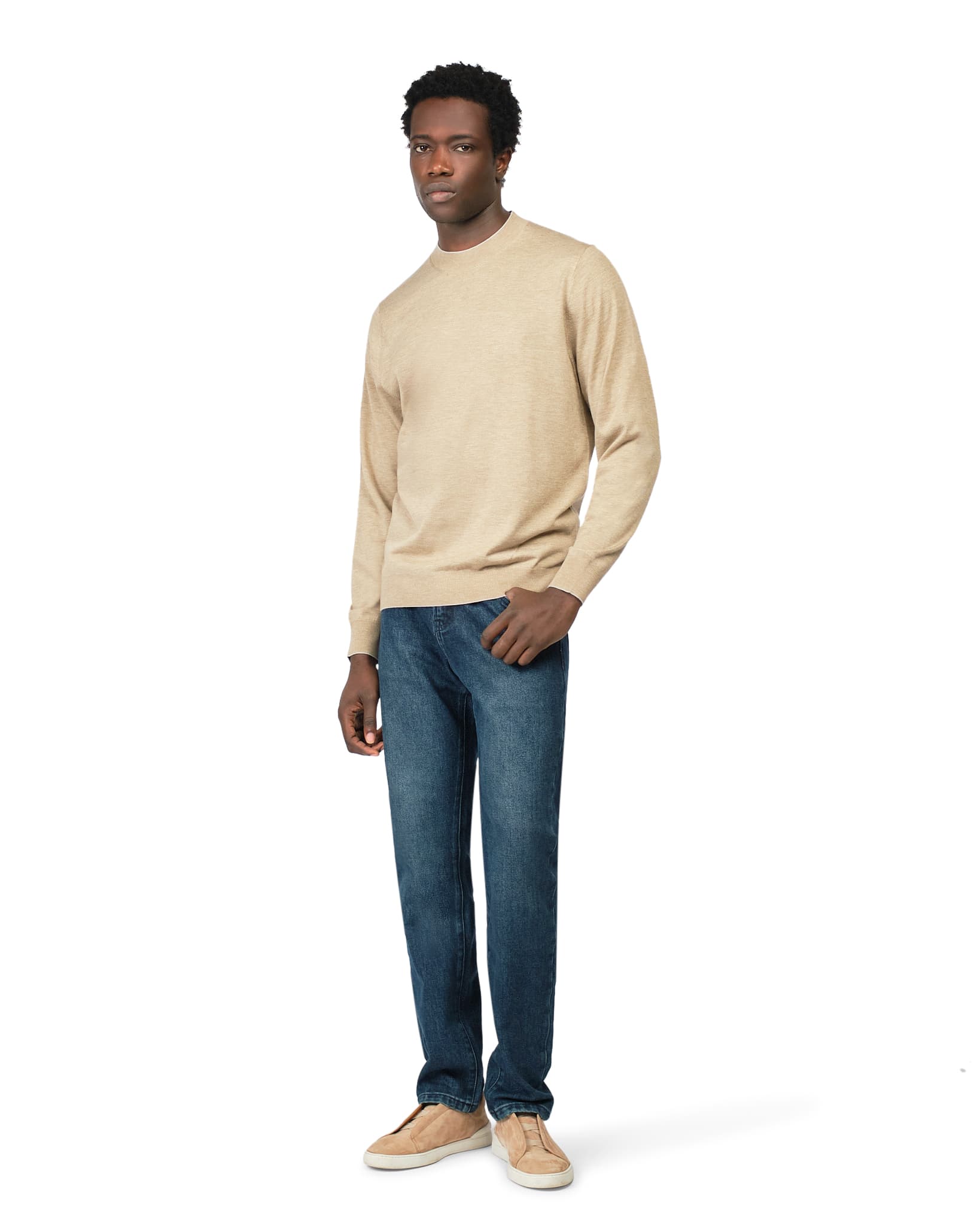 Man wearing a beige sweater and blue jeans on a white background