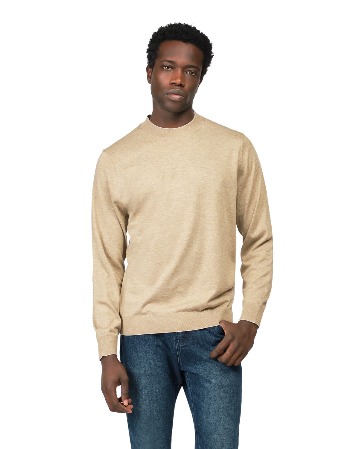 Man wearing a beige sweater and blue jeans on a white background