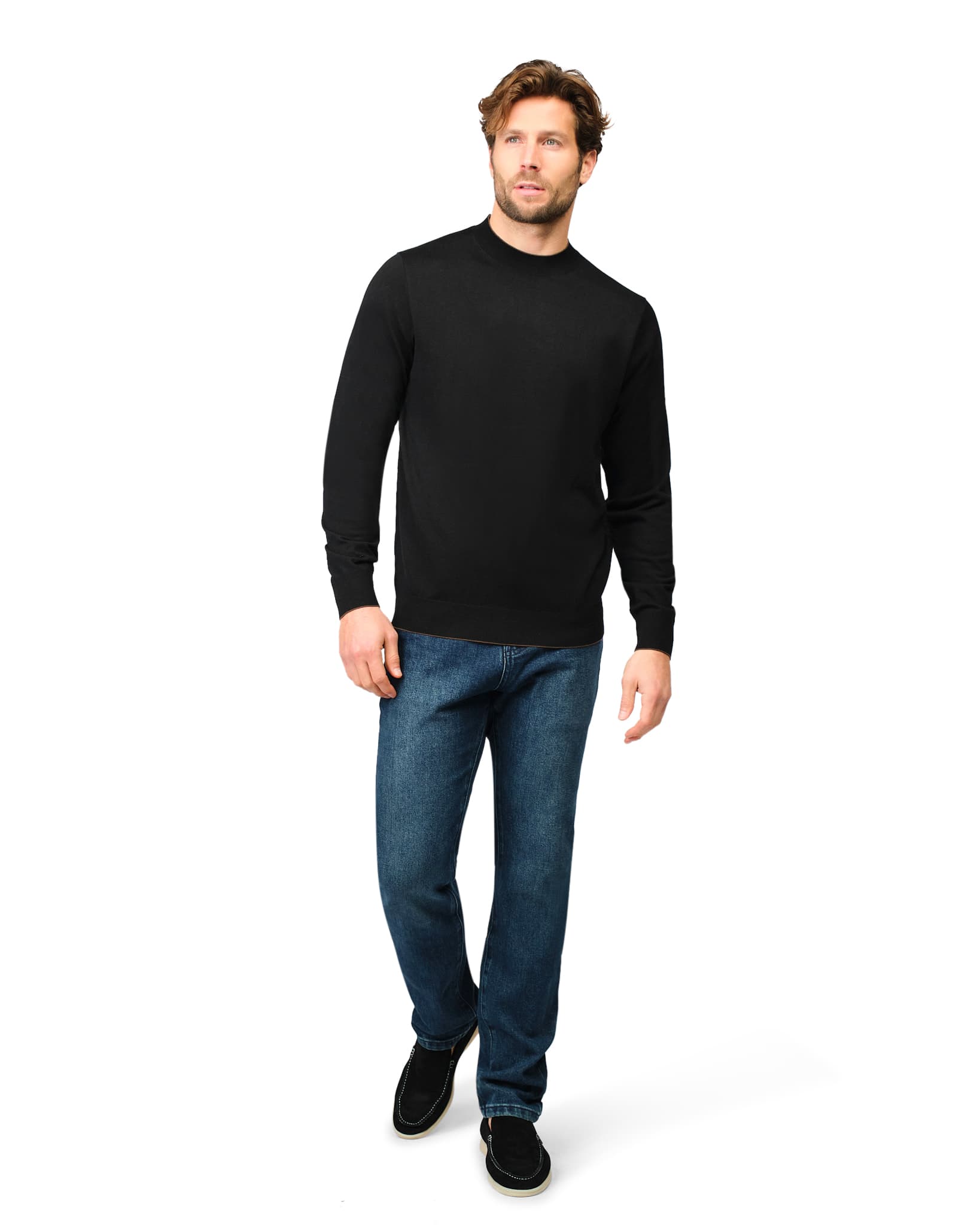 Man wearing a black sweater and blue jeans on a white background