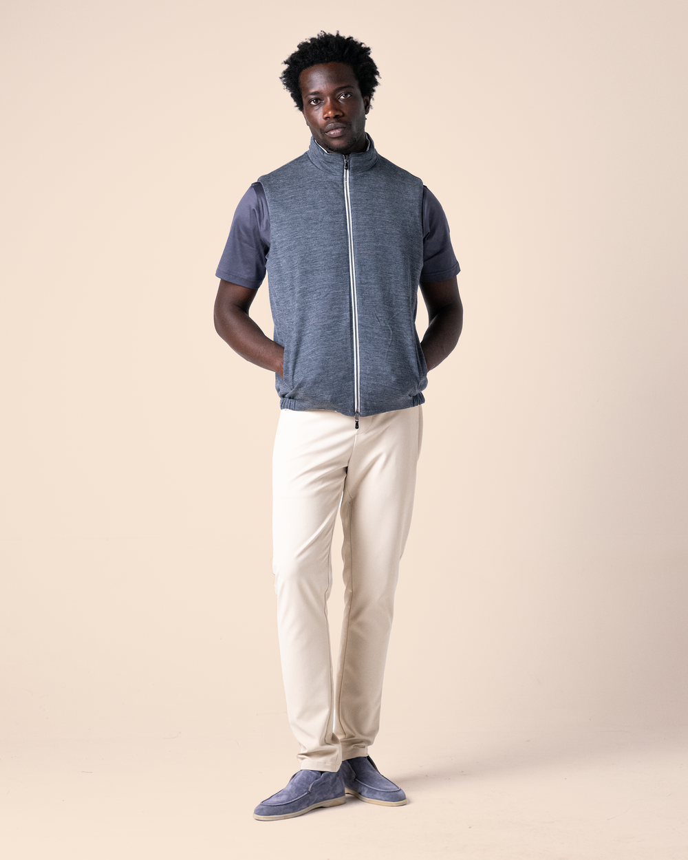 Man wearing a blue zip-up shirt and beige pants on a beige background