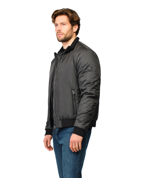 Man wearing a dark gray jacket and blue jeans on a white background
