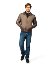 Man wearing a brown bomber jacket and blue jeans on a white background