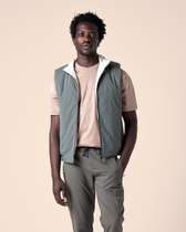 Man wearing a green vest over a beige shirt on a beige background