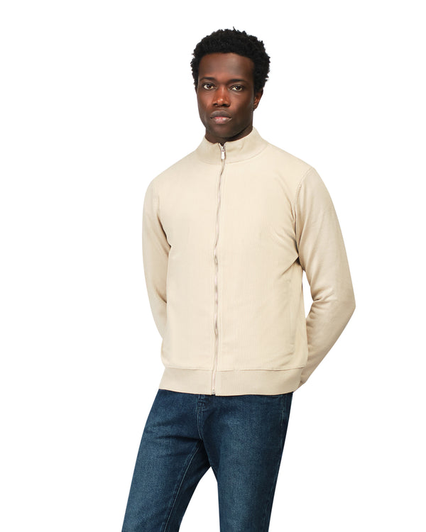 Man wearing a beige jacket and blue jeans on a white background