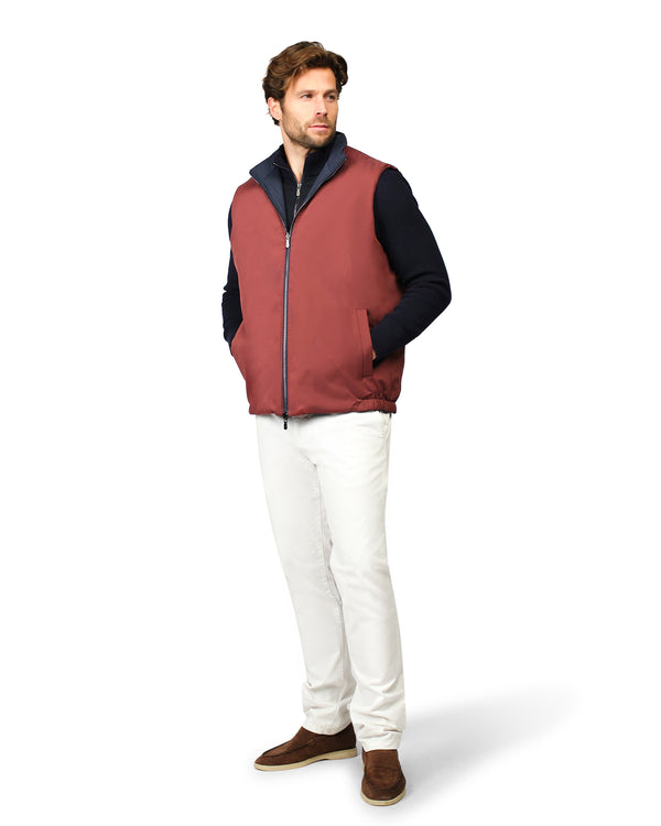 Man wearing a red and black jacket with white pants on a white background