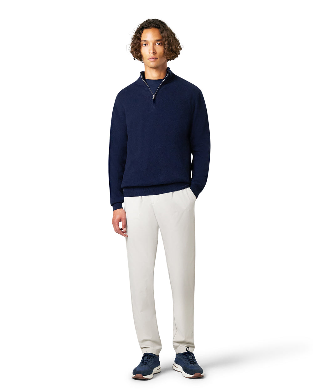 Man wearing a navy sweater and white pants 