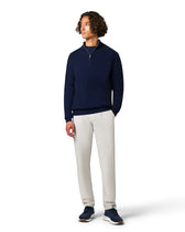 Man wearing a navy sweater and light gray pants 