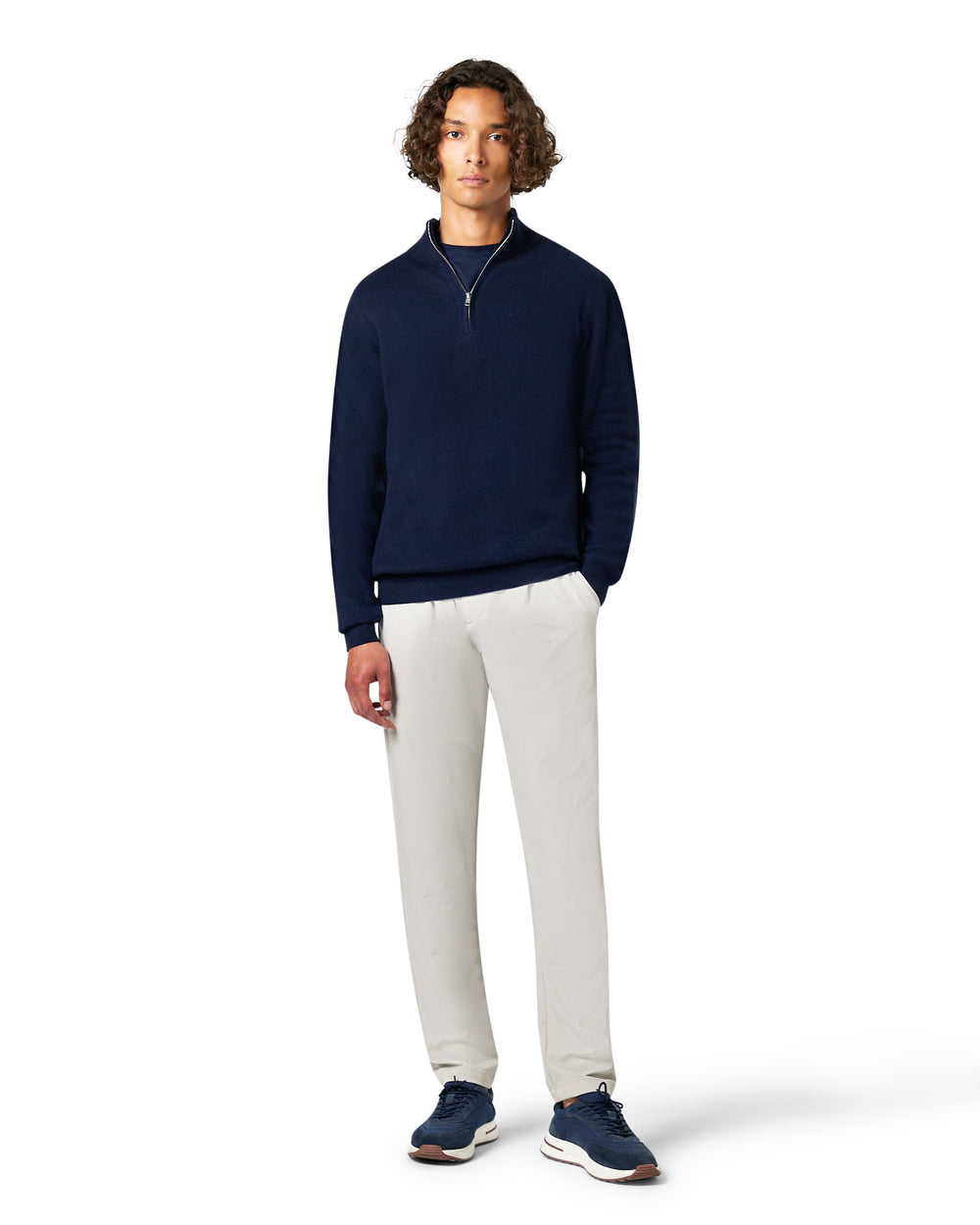 Man wearing a navy sweater and white pants 
