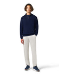 Man wearing a navy sweater and white pants 