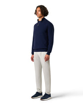 Man wearing a navy sweater and white pants 
