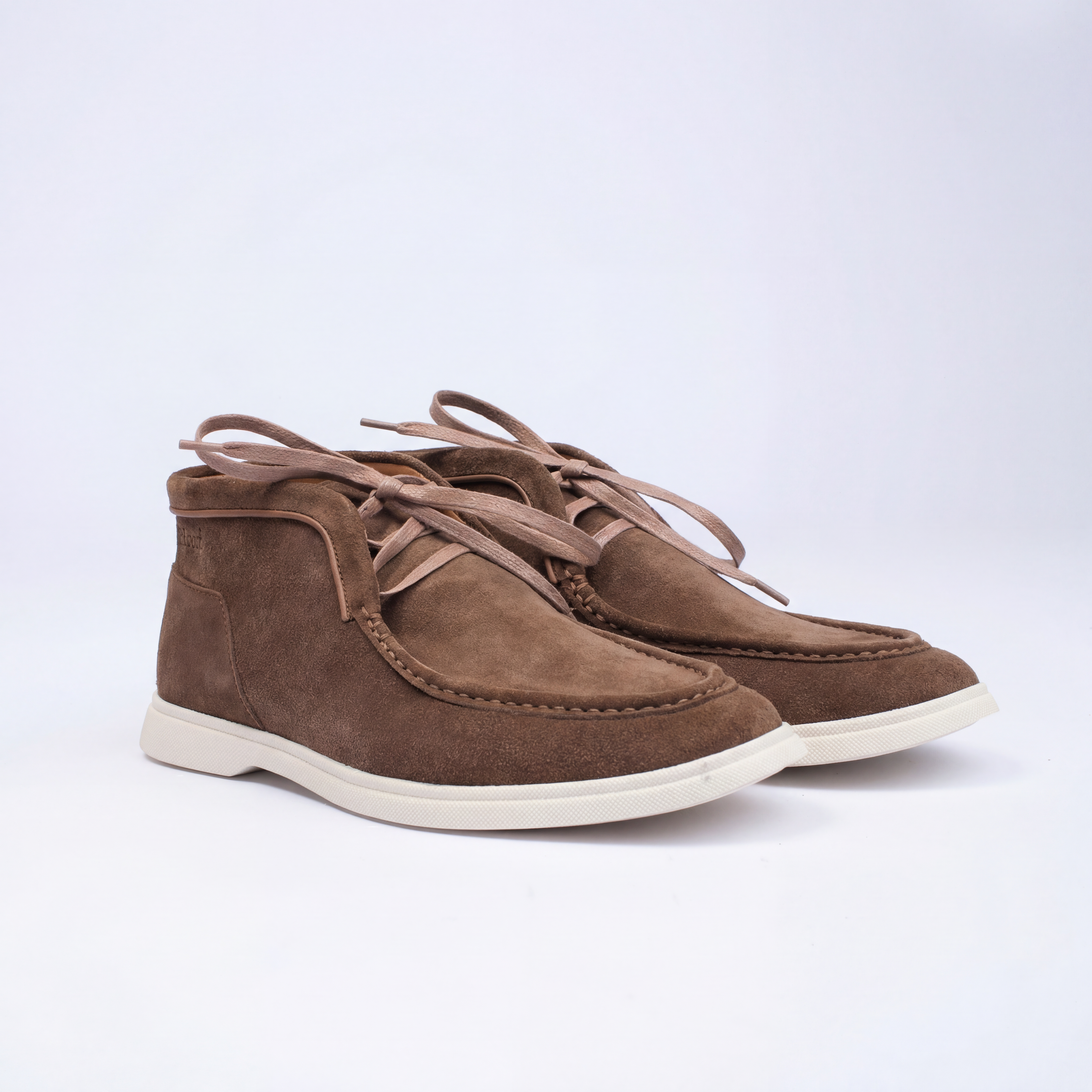 Pair of brown suede shoes with white soles on a light gray background
