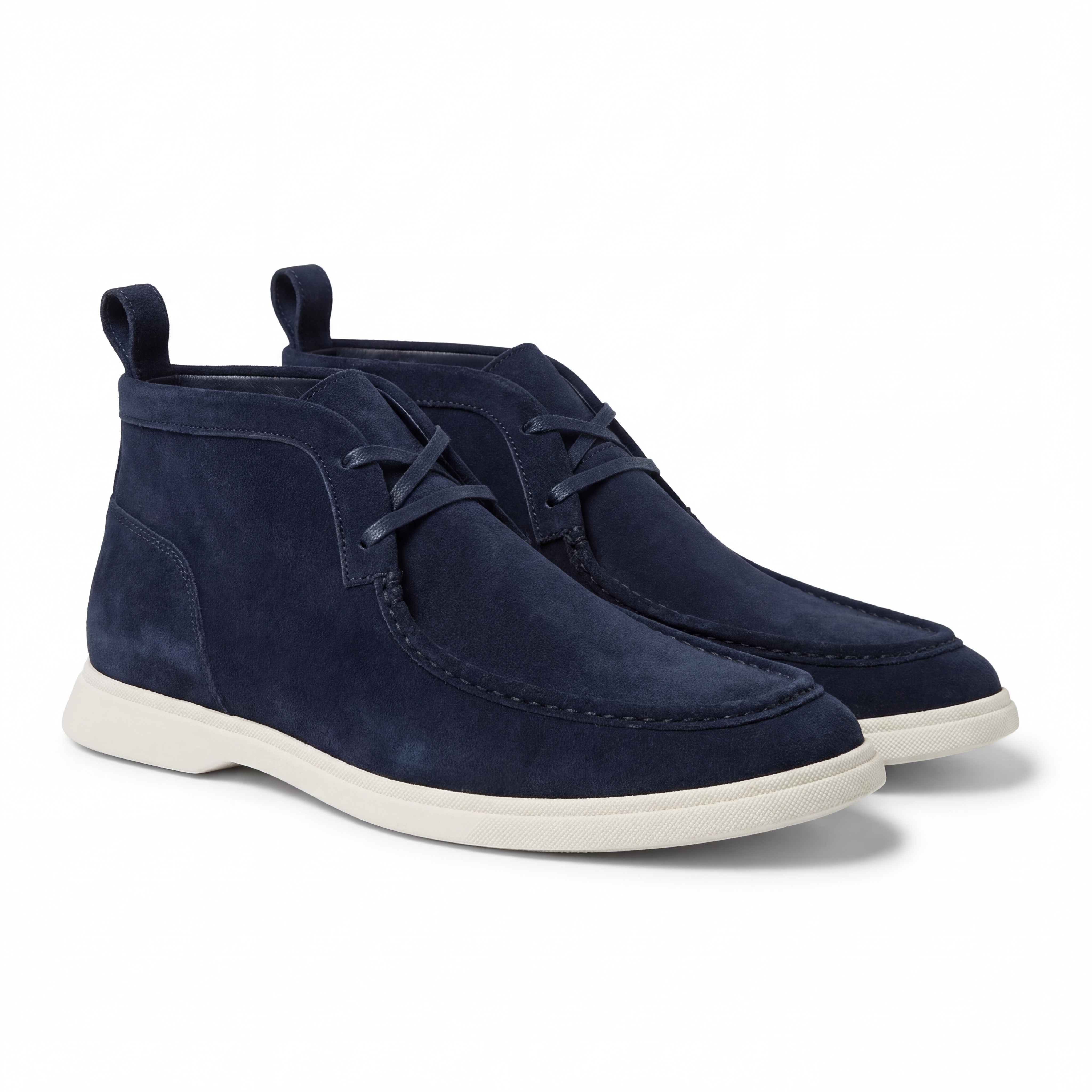 Navy blue suede chukka boots with white soles on a white background