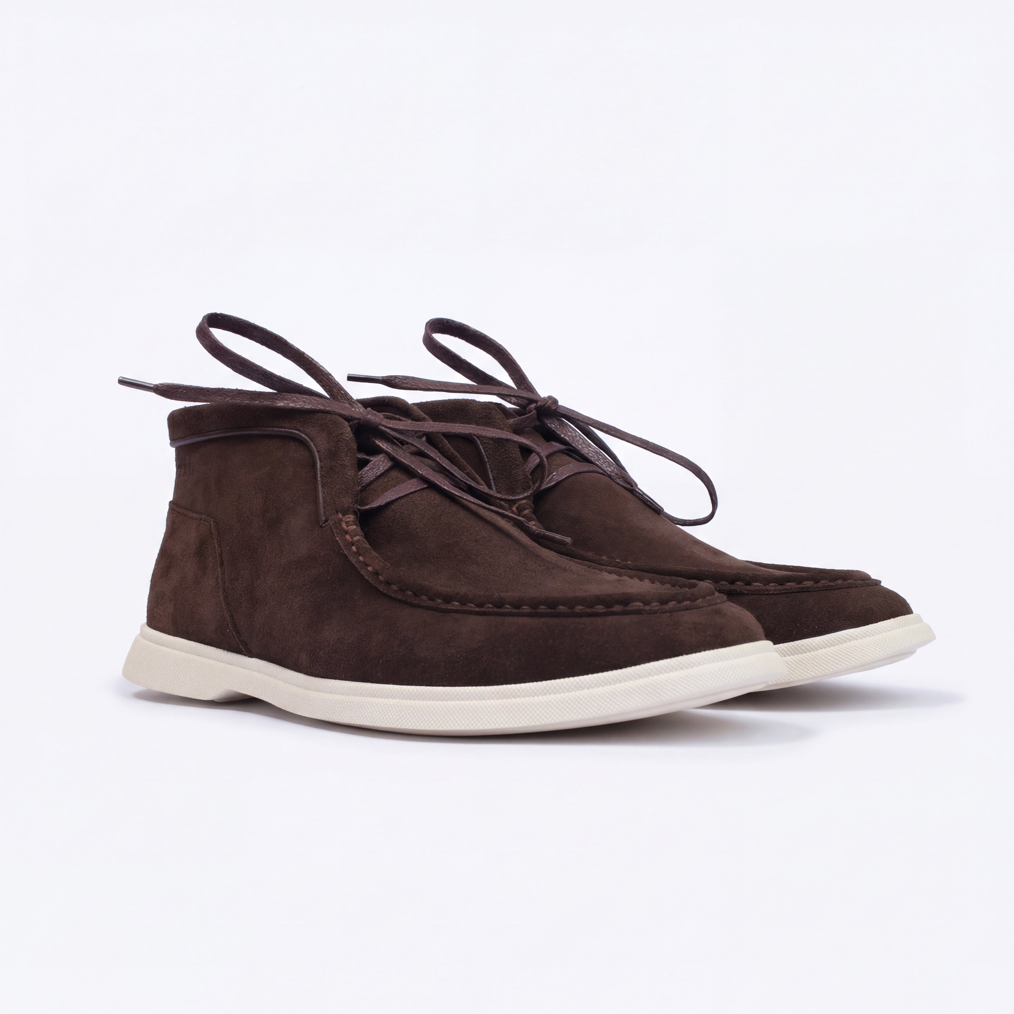 Brown suede shoes with white soles on a light purple background