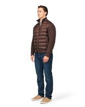Man wearing a brown puffer jacket and blue jeans on a white background